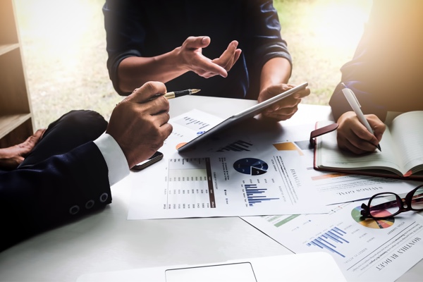 Three people having a discussion around a table and documents